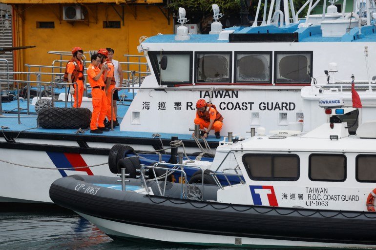 Taiwan Coast Guard members pose for pictures while onboard a boat moored at a fishing harbour near Keelung, Taiwan, on July 24, 2024. (REUTERS/Carlos Garcia Rawlins)