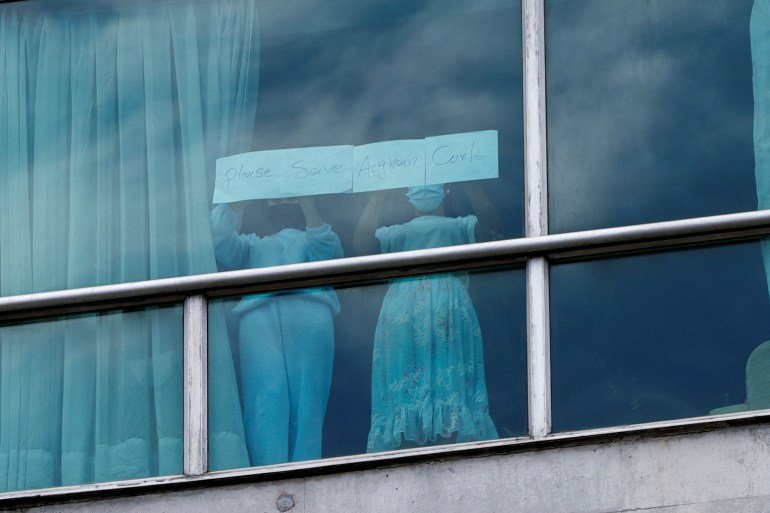 Women hold a sign at a hotel where migrants from Asia and the Middle East are housed after being deported to Panama as part of an agreement between the administration of U.S. President Donald Trump and the Central American nation, in Panama City, Panama February 18, 2025.