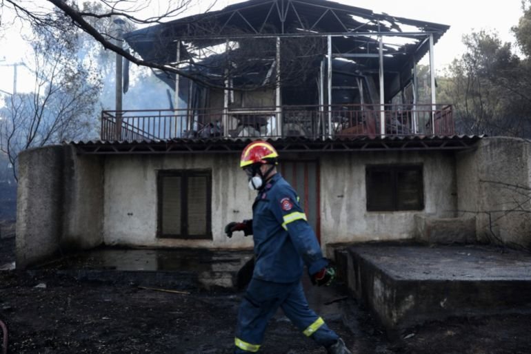 A firefighter walks past a burned house after a wildfire swept through Pikermi suburb, east of Athens, Greece, 03 July 2025. [George Vitsaras/EPA]